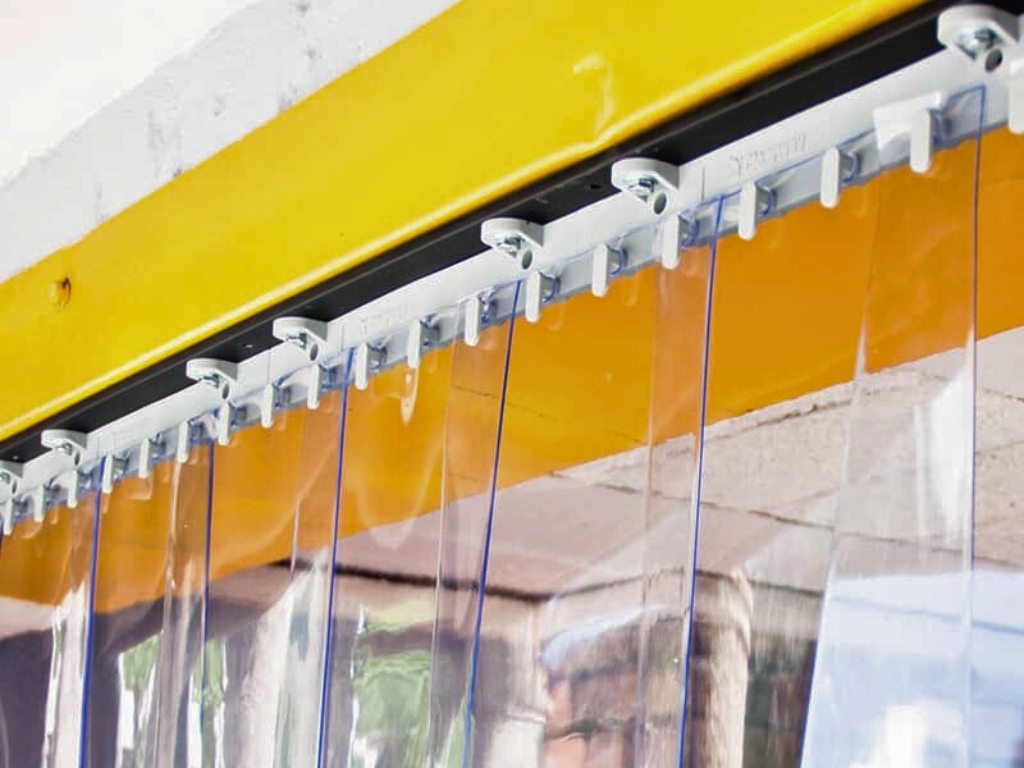 Close up of clear pvc strip curtain mounted on a metal hanging rail.