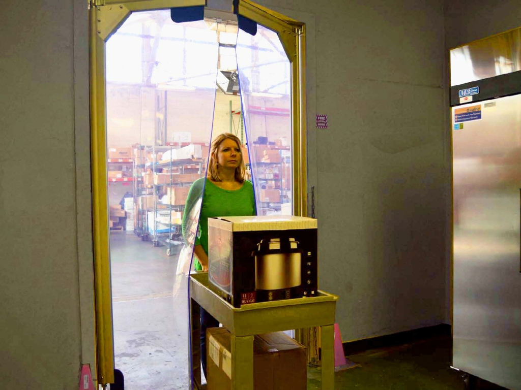 Worker pushing cart with boxes through clear swing pvc doors in warehouse. File name: worker cart swing pvc doors warehouse.jpg